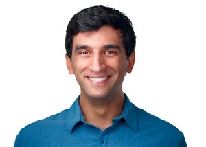 professor wearing a blue button up shirt in front of a white backdrop